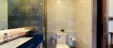Un baño moderno con lavamanos de mármol, inodoro y ducha.
