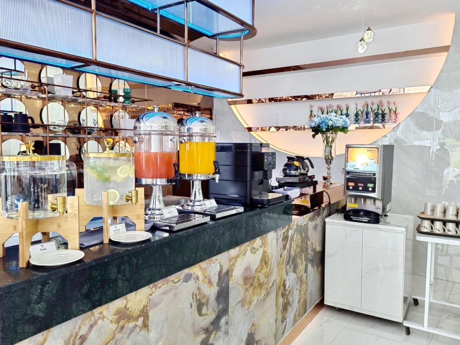 Un área de bar moderna con mostrador de mármol, una máquina de café y una variedad de bebidas.