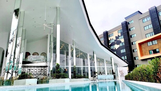 Ein modernes Gebäude mit Poolbereich, großen Glasfenstern und markantem architektonischen Design.
