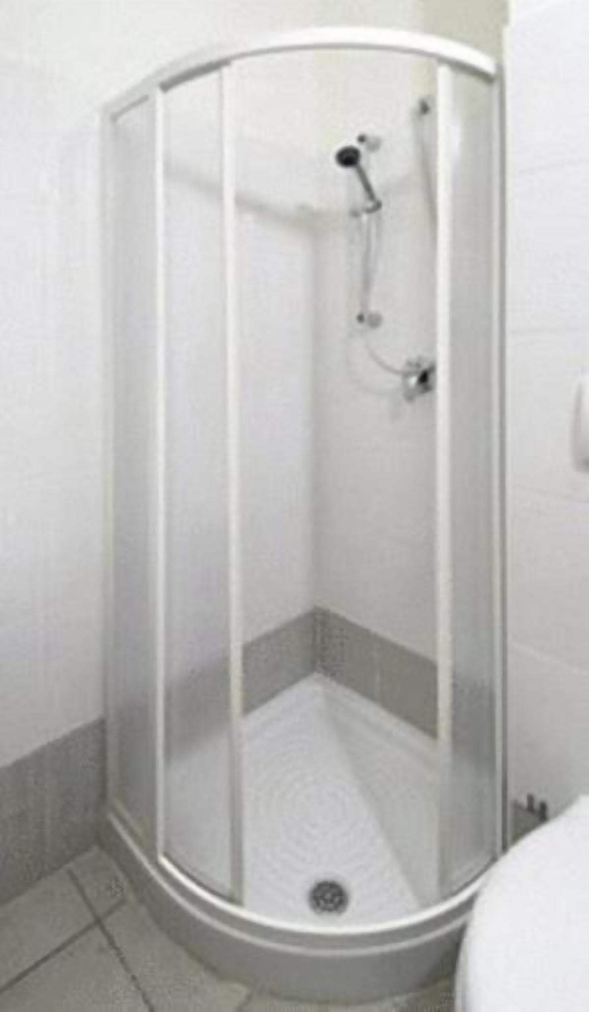 Un box de ducha en esquina con puerta de cristal y ducha.