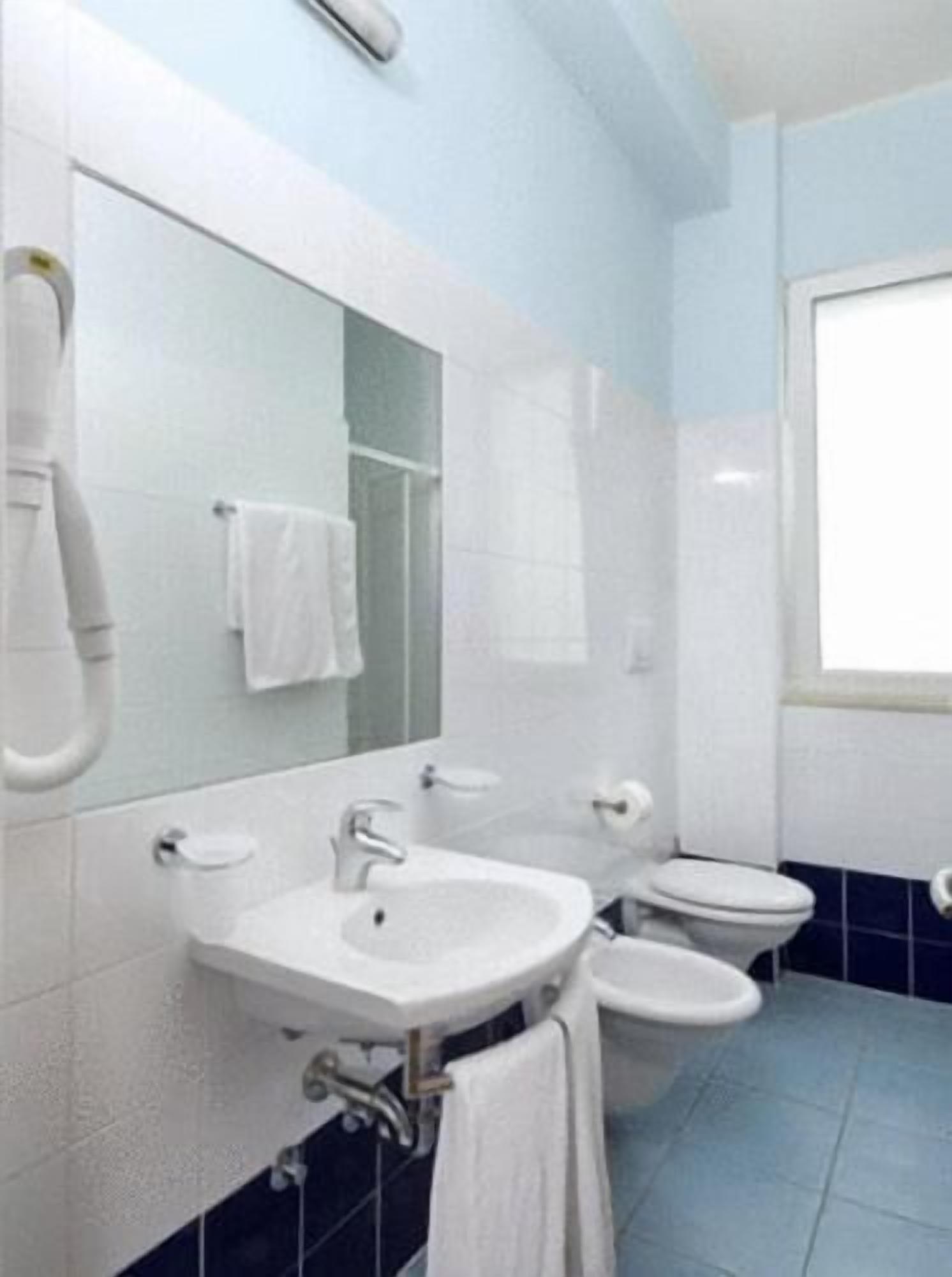 Une salle de bain avec un lavabo, des toilettes et un miroir.
