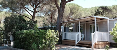 A small, single-story cabin with a porch and a covered outdoor seating area.