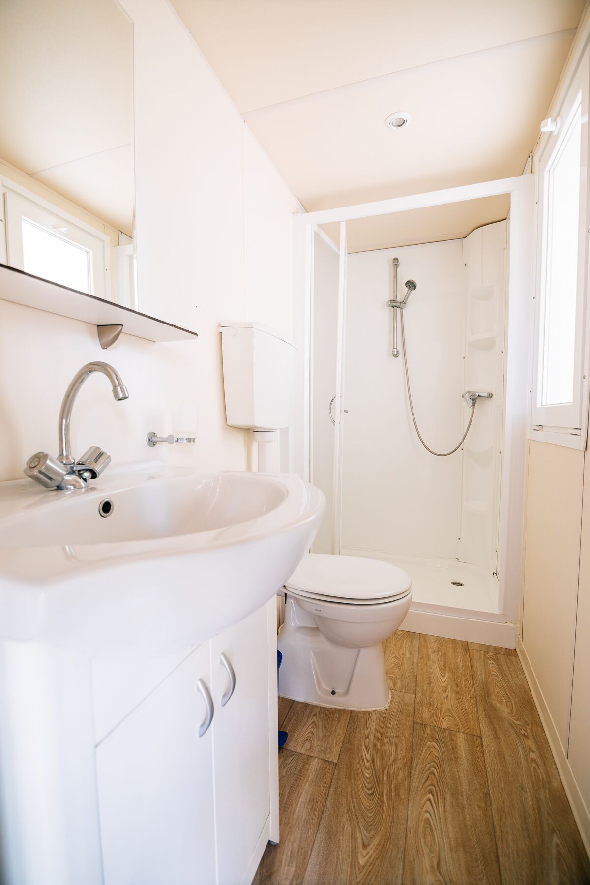 A compact bathroom with a sink, toilet, and shower.