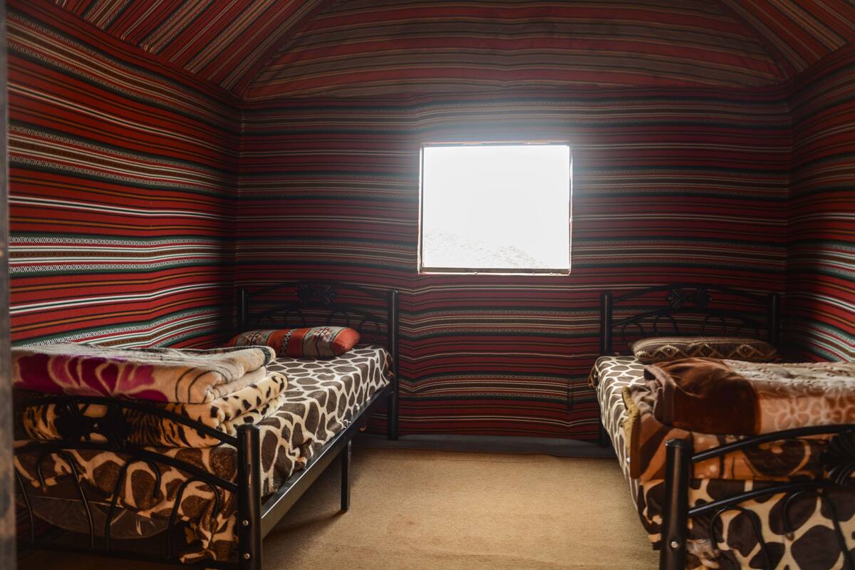 Une chambre avec deux lits, une fenêtre et des murs à rayures.