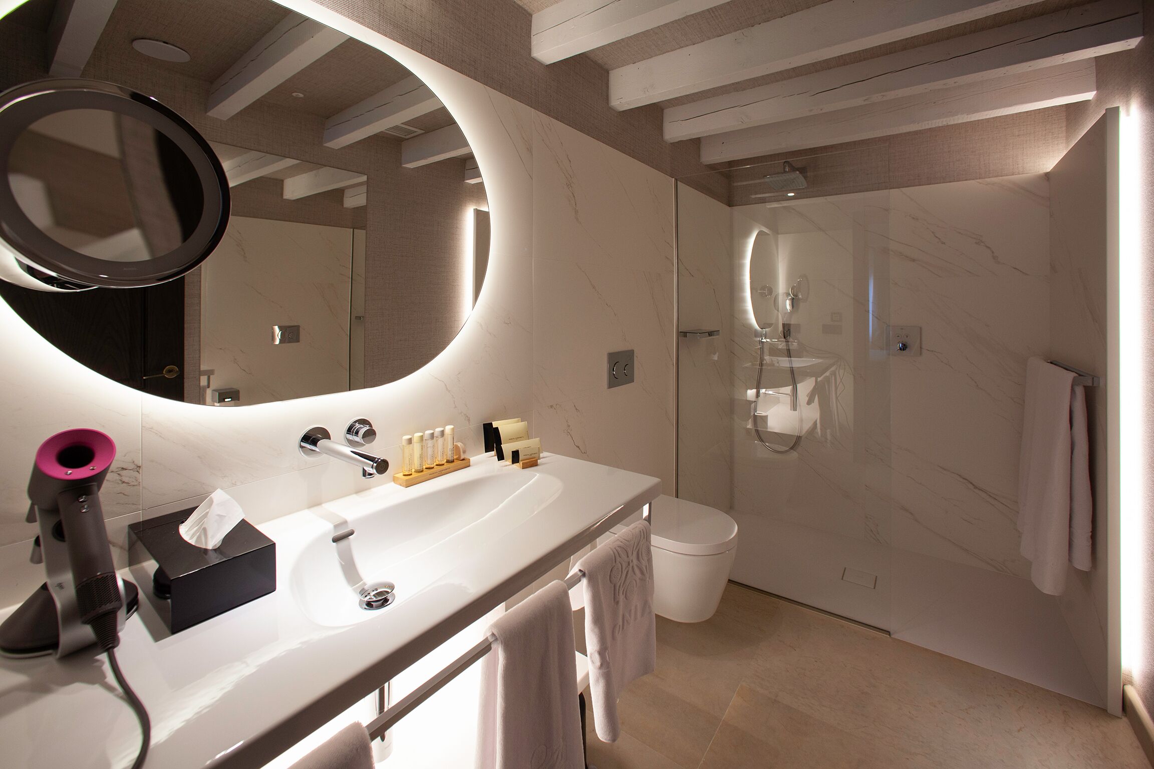 Une salle de bain moderne avec un grand miroir, un lavabo et un espace douche.