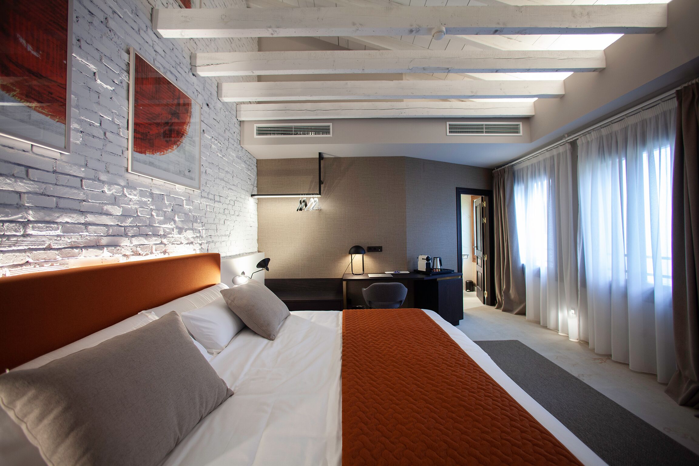 Una habitación de hotel moderna con una cama grande, un escritorio y vistas a la ciudad.