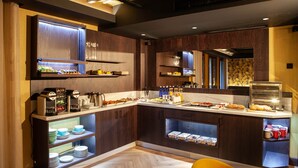 A modern kitchen with built-in appliances, wooden cabinetry, and a breakfast bar. - Colonial Palace (León)