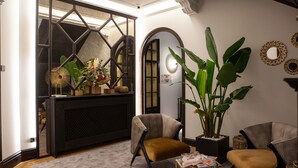 A modern living room with a large plant, two armchairs, a coffee table, and a fireplace. - Colonial Palace (León)