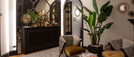 A modern living room with a large plant, two armchairs, a coffee table, and a fireplace.