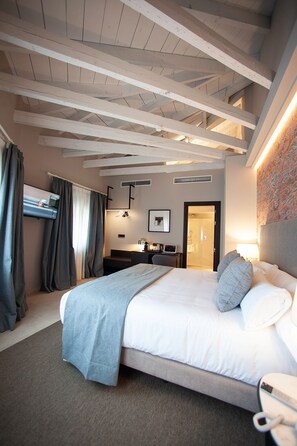A modern hotel room with a large bed, a desk, a flat-screen TV, and a bathroom visible through an open door.
