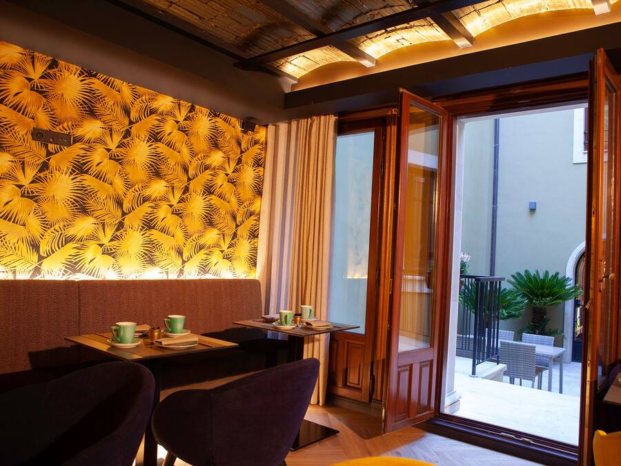 A cozy dining area with a patterned wall, a table with cups and saucers, and a view of the outdoor patio.