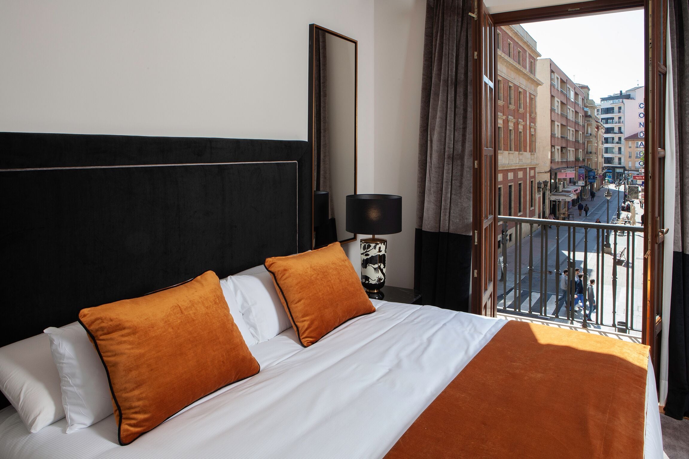 Una camera d'albergo con un letto grande, un comodino, una lampada e vista sulla strada.