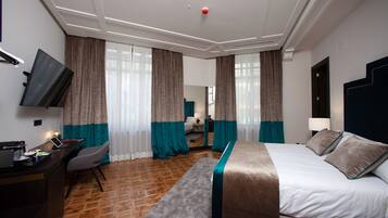Ein Hotelzimmer mit Bett, Schreibtisch, Stuhl und Fernseher an der Wand.