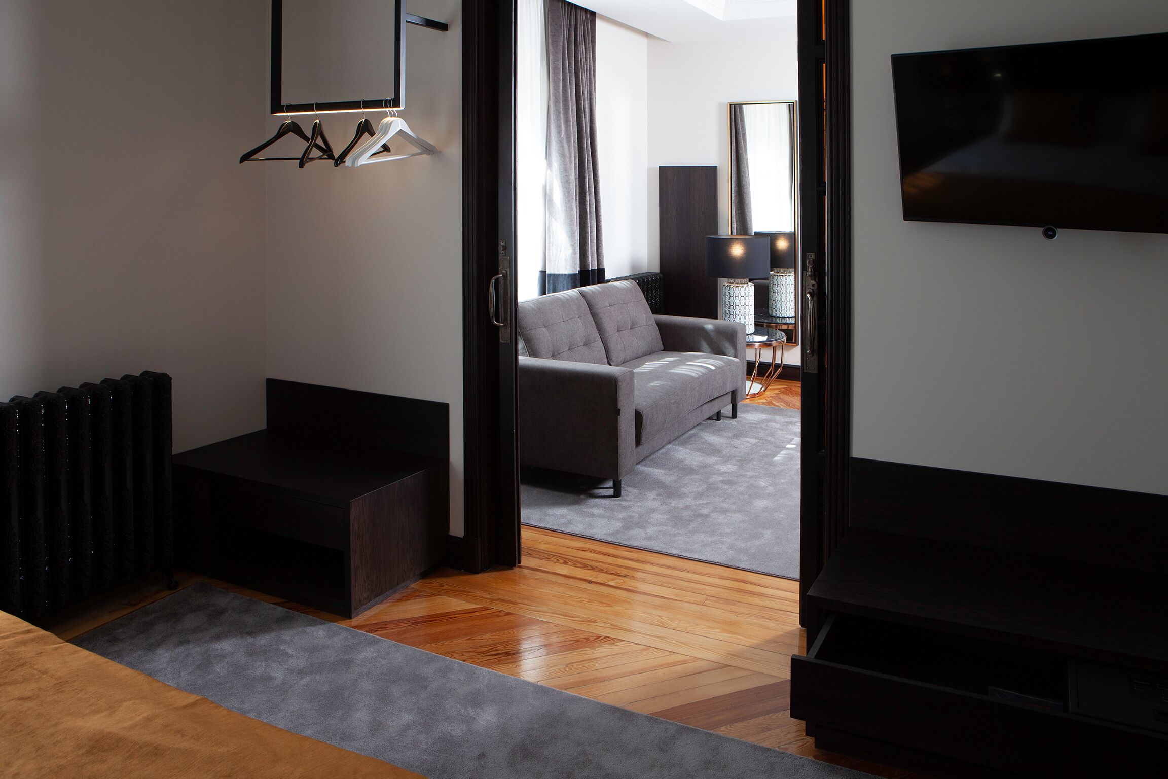 Una sala de estar moderna con un sofá gris, un mueble de entretenimiento negro y un televisor de pantalla plana montado en la pared.