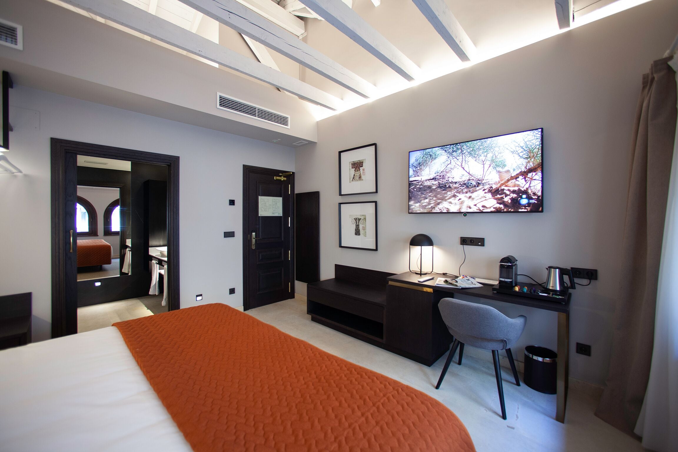 Una habitación de hotel con una cama grande, un escritorio con silla, un televisor y un sofá.