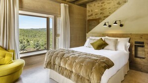 A bedroom with a large bed, a yellow armchair, and a view of the outdoors. - Torre del Marqués Hotel Spa & Winery - Small Luxury Hotels (Monroyo)