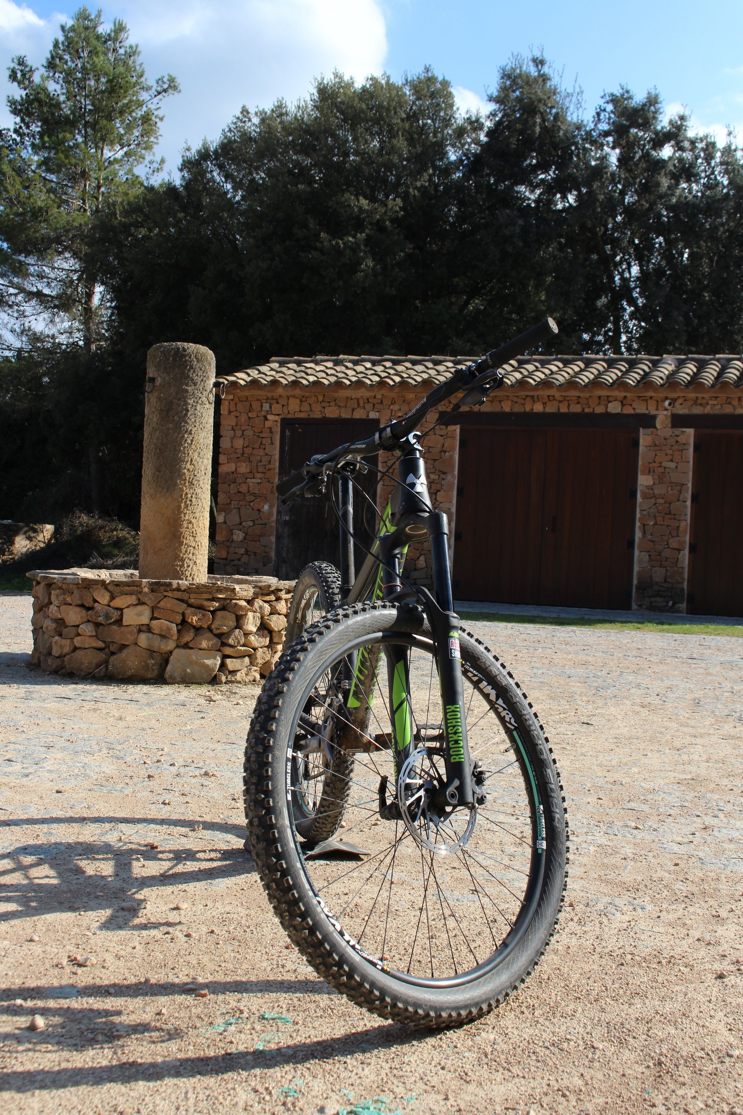 Una bicicleta de montaña estacionada frente a un edificio de piedra con tejado de tejas.