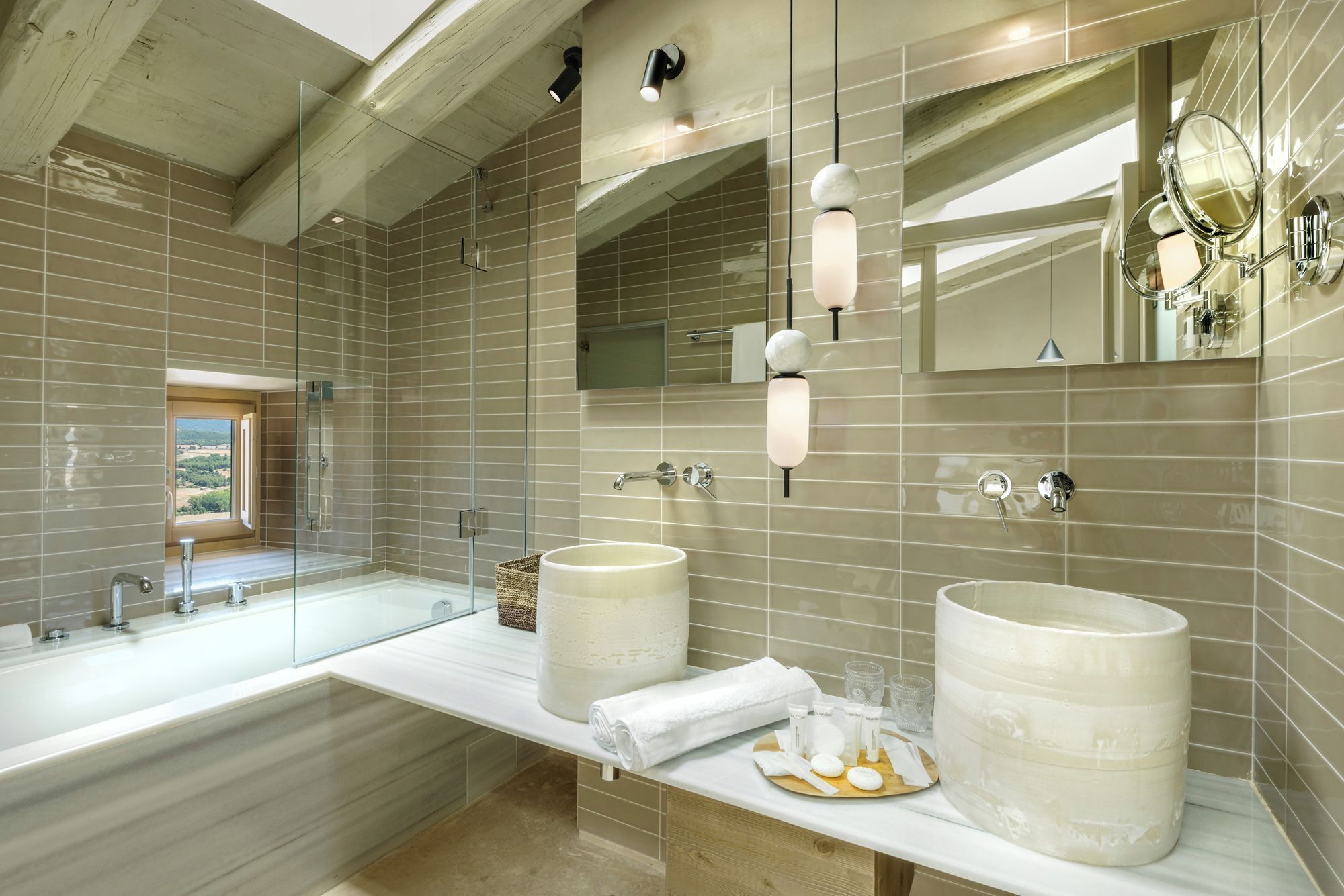 Un baño moderno con dos lavamanos grandes, un box de ducha de cristal y un espejo amplio.