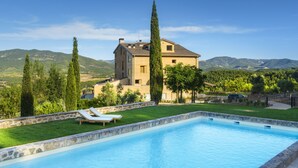 A swimming pool with lounge chairs, a stone wall, and a large house with a tiled roof. - Torre del Marqués Hotel Spa & Winery - Small Luxury Hotels (Monroyo)