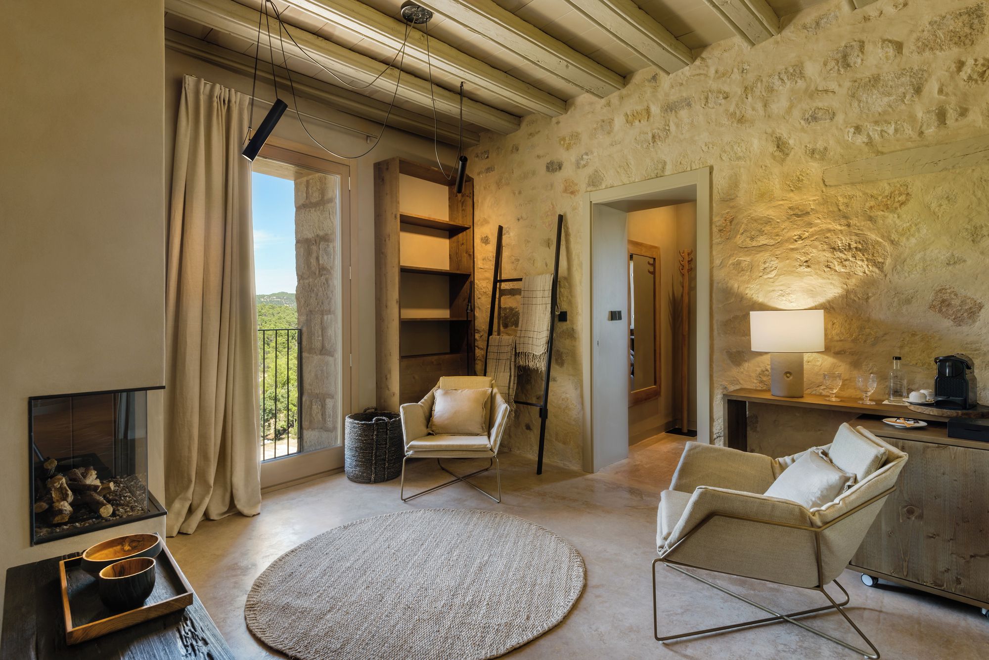 Una habitación con chimenea, un tapete redondo y vistas al exterior.