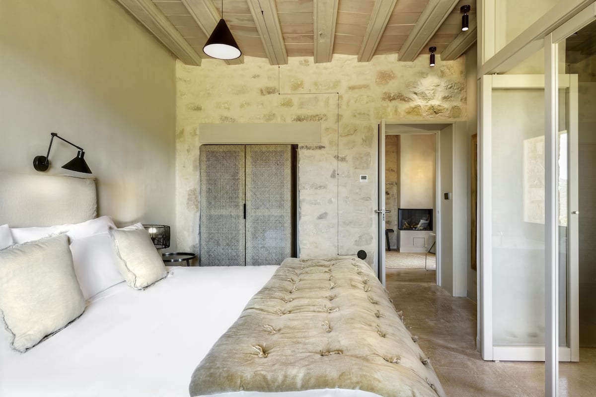 Quarto com uma cama grande, luminária de cabeceira, armário e porta para outro cômodo.
