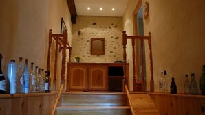 Un escalier en bois, un mur en pierre et un meuble en bois contenant des bouteilles.