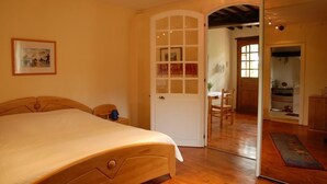 Une chambre à coucher avec un lit en bois, une porte blanche et une vue sur une autre pièce, grâce à une porte ouverte.