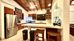A modern kitchen with wooden cabinets, stainless steel appliances, and a central island with stools.
