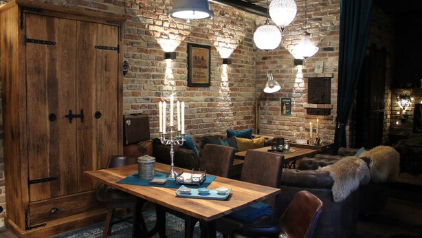 A cozy dining area with a wooden table, chairs, and a brick wall backdrop. - Friendly Home - Special apartment "Old Bakery" (Dersdorf)