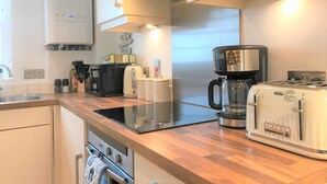 A modern kitchen with stainless steel appliances, a coffee maker, and a toaster. - Seaside Cottage With Parking (Worthing)