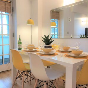 A dining area with a white table set for four, yellow chairs, and a large mirror above the table. - Seaside Cottage With Parking (Worthing)