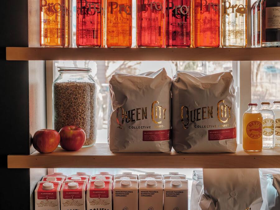 Des étagères remplies de bouteilles, de paquets de café et de briques de lait d’amande.