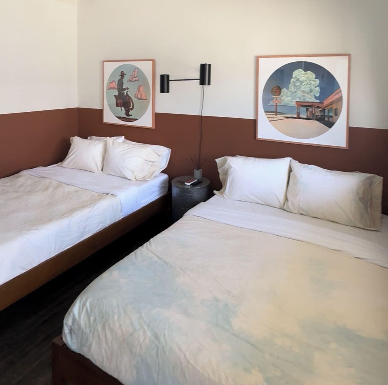 Ein Hotelzimmer mit zwei Betten, einem Nachttisch und zwei gerahmten Bildern an der Wand.