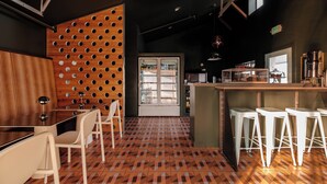 A restaurant with a bar area, white bar stools, a patterned floor, and a wooden wall with circular cutouts. - Mellow Moon Lodge (Del Norte)