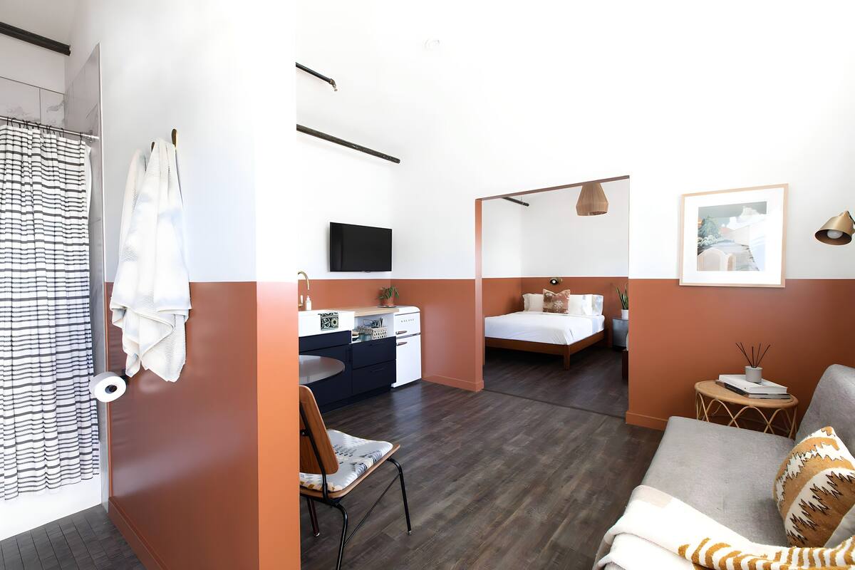 A modern room with a bed, a desk, a chair, and a TV.