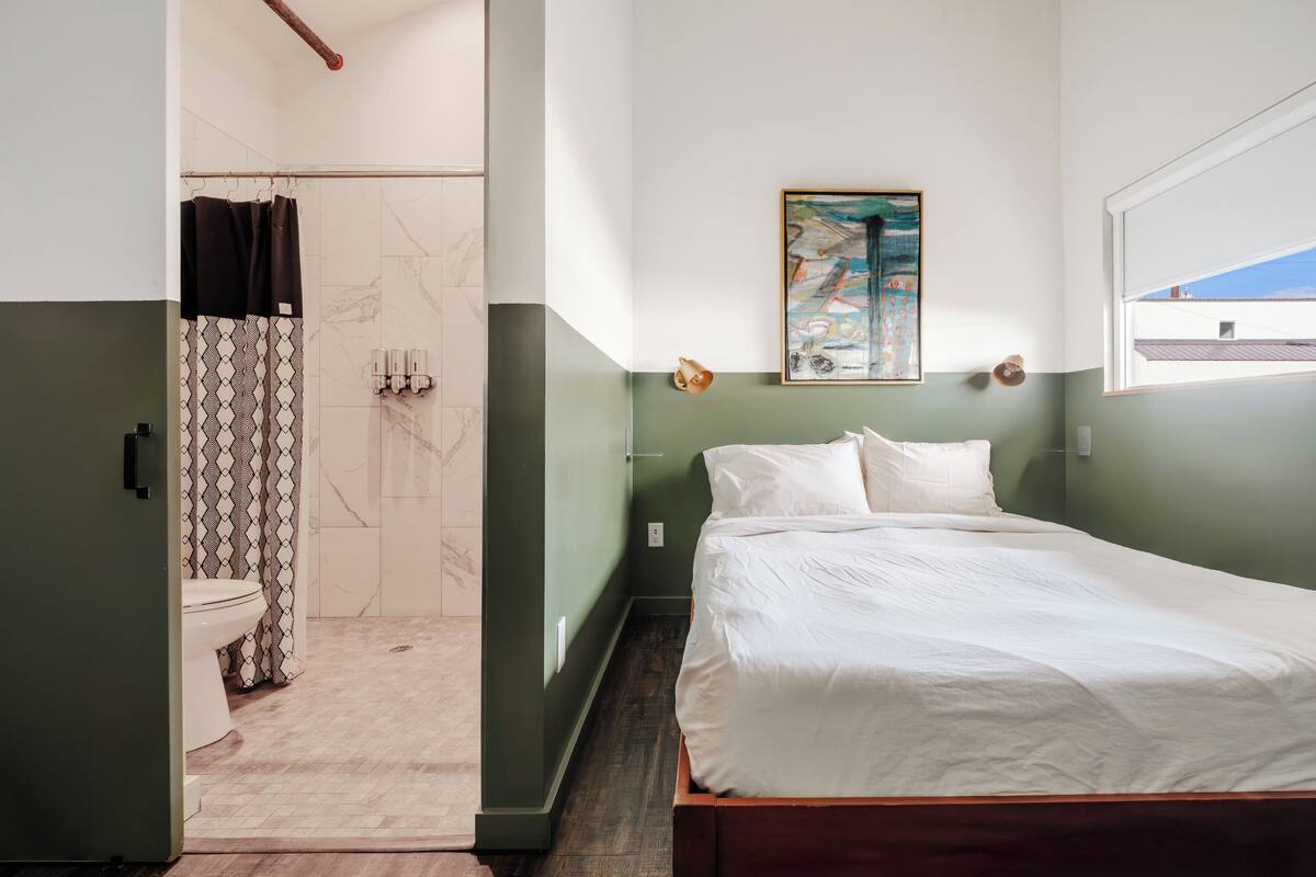 A bedroom with a bed, a shower, and a toilet.
