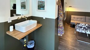 A modern bathroom with a large mirror, a white sink, and a wooden vanity. - Mellow Moon Lodge (Del Norte)