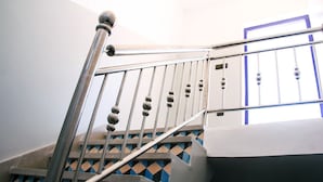 A staircase with a metal handrail and a geometric patterned wall. - Dar Iziki (Sidi Kaouki)