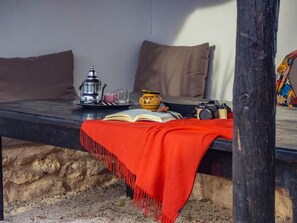 A bed with a red blanket, a book, a camera, and a teapot on a wooden bench. - Dar Iziki (Sidi Kaouki)
