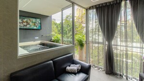 A modern room with a large window, a black leather sofa, a mounted artwork, and a potted plant. - Haven, A Design Hotel (Medellín)