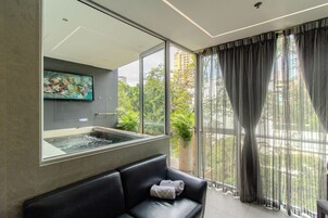 Una habitación moderna con un ventanal grande, un sofá de cuero negro, una obra de arte colgada y una planta en maceta.
