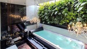 A luxurious bathroom with a marble vanity, a freestanding bathtub, and a large green plant wall. - Haven, A Design Hotel (Medellín)