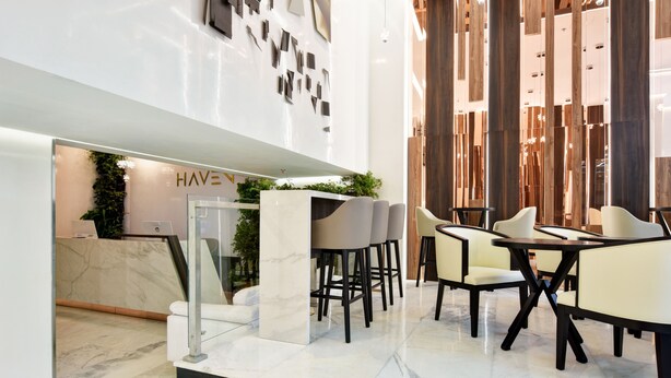 A modern interior with marble flooring, a reception area, and a seating area with tables and chairs. - Haven, A Design Hotel (Medellín)