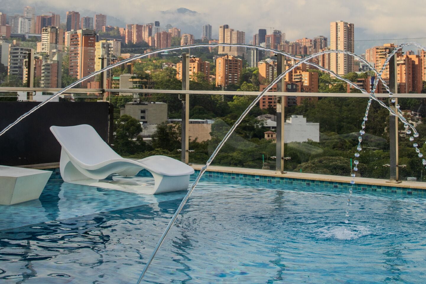 Piscina en la azotea con vistas a un paisaje urbano, que incluye edificios altos y zonas verdes.