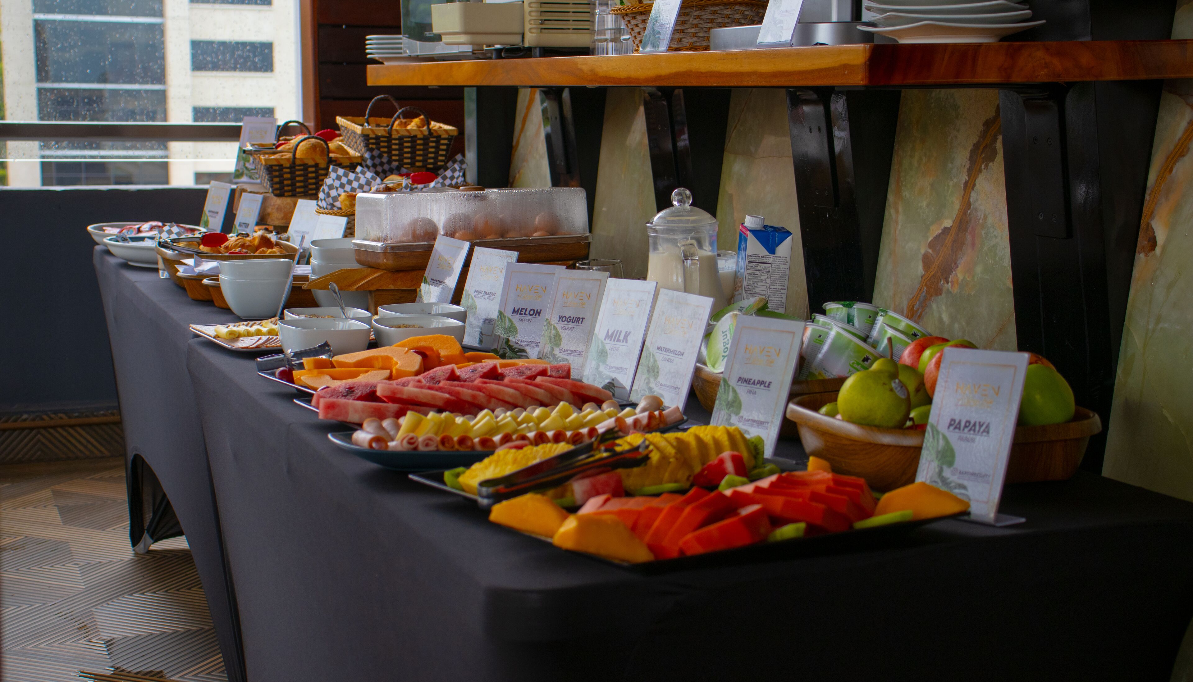 A buffet table with various food items and labels indicating different types of milk and juices.