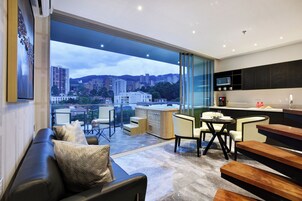 Una sala de estar moderna con un ventanal grande, un sofá, una mesa de comedor y una zona de cocina con microondas.