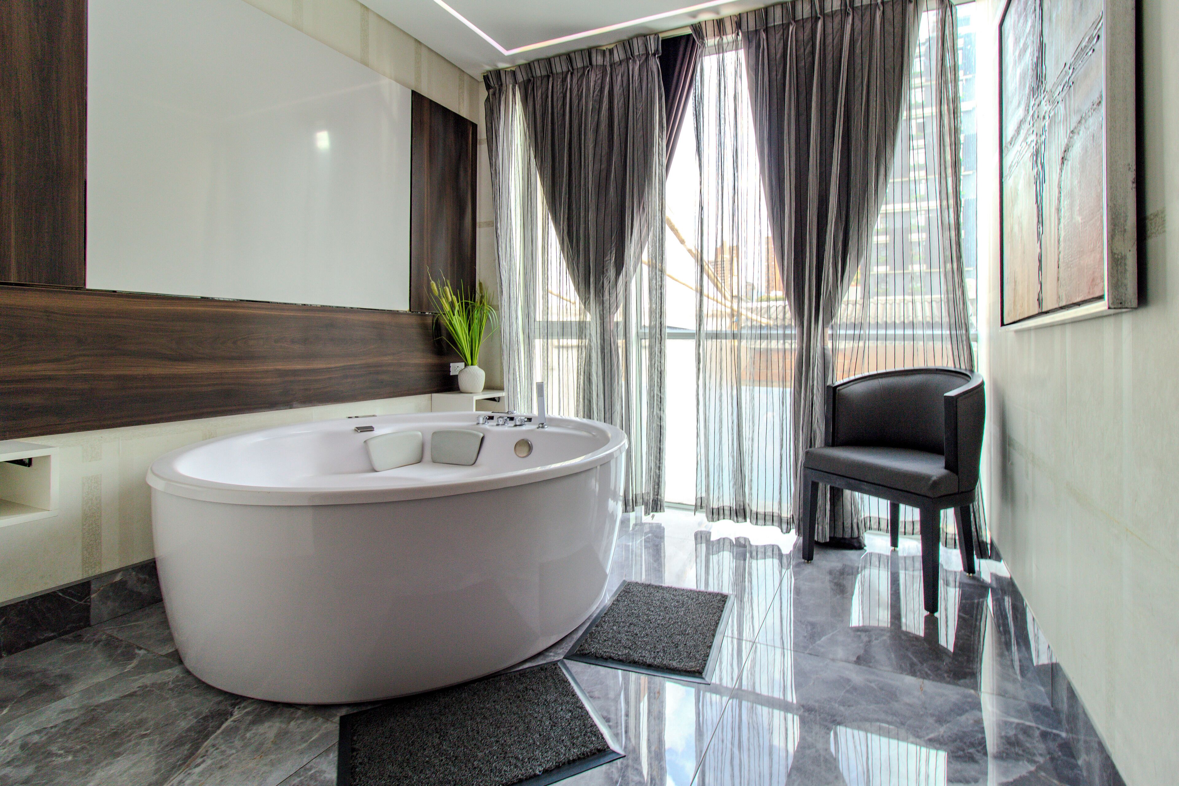 Un baño moderno con una bañera grande, una silla y una planta en maceta.