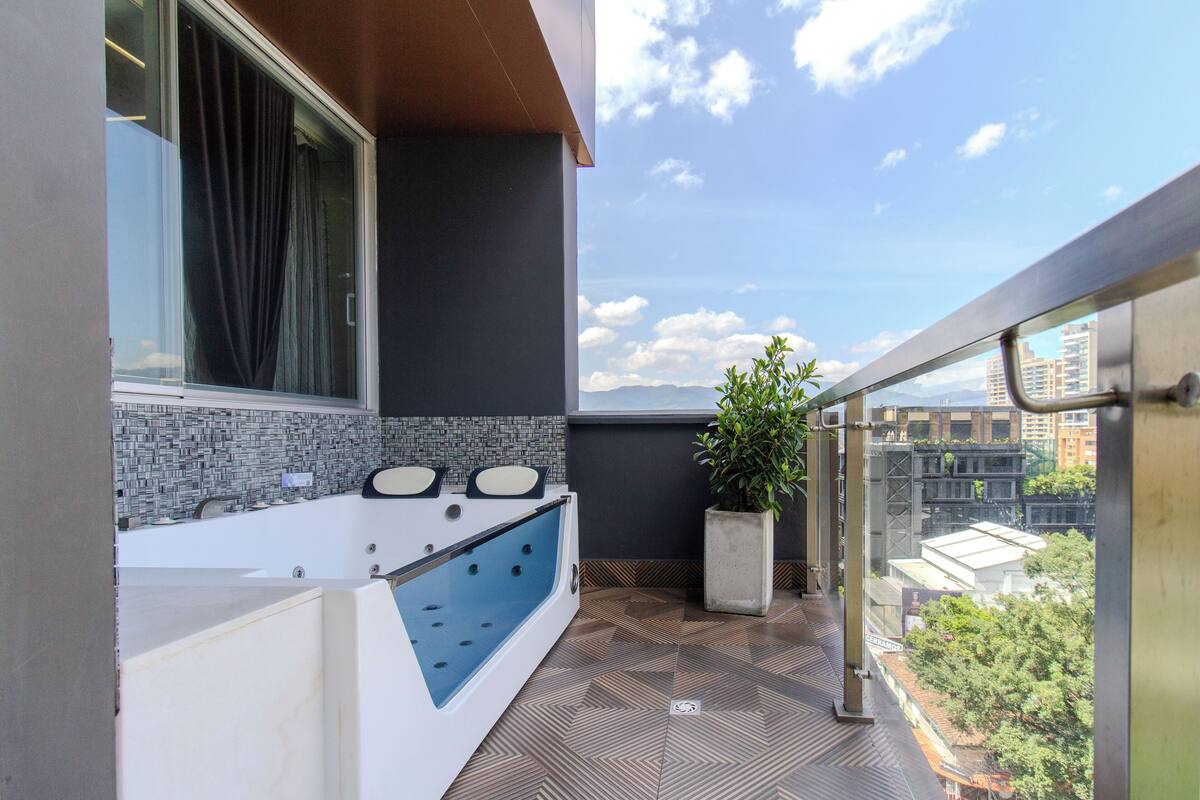 Un baño moderno con bañera, una planta en maceta y vistas a la ciudad.