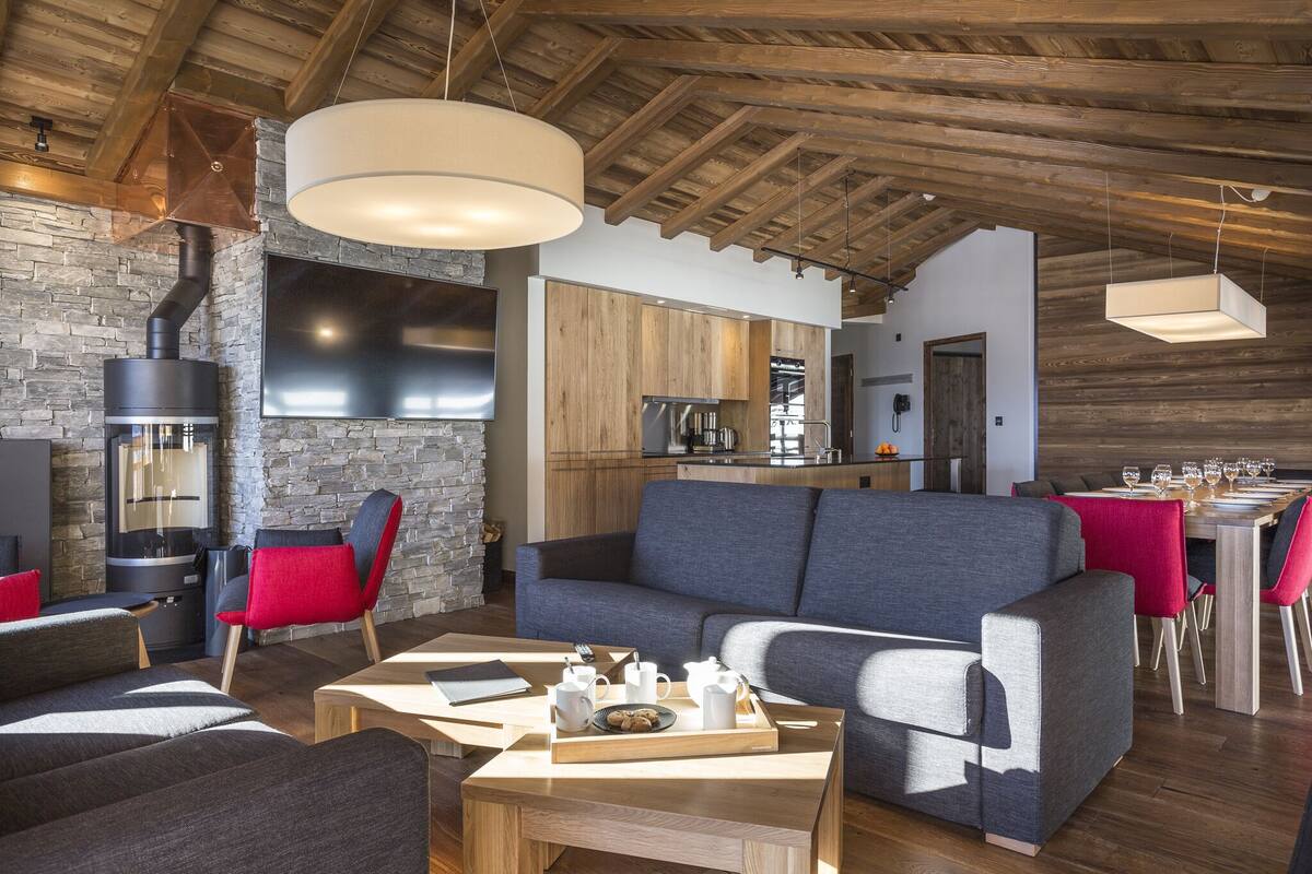 A modern living room with a stone fireplace, a large sofa, and a dining area with a table set for a meal.