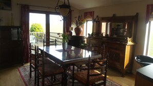 A dining area with a glass table, wooden chairs, and a large vase with flowers. - Greenacres Holiday Cabins (St. Andrews)